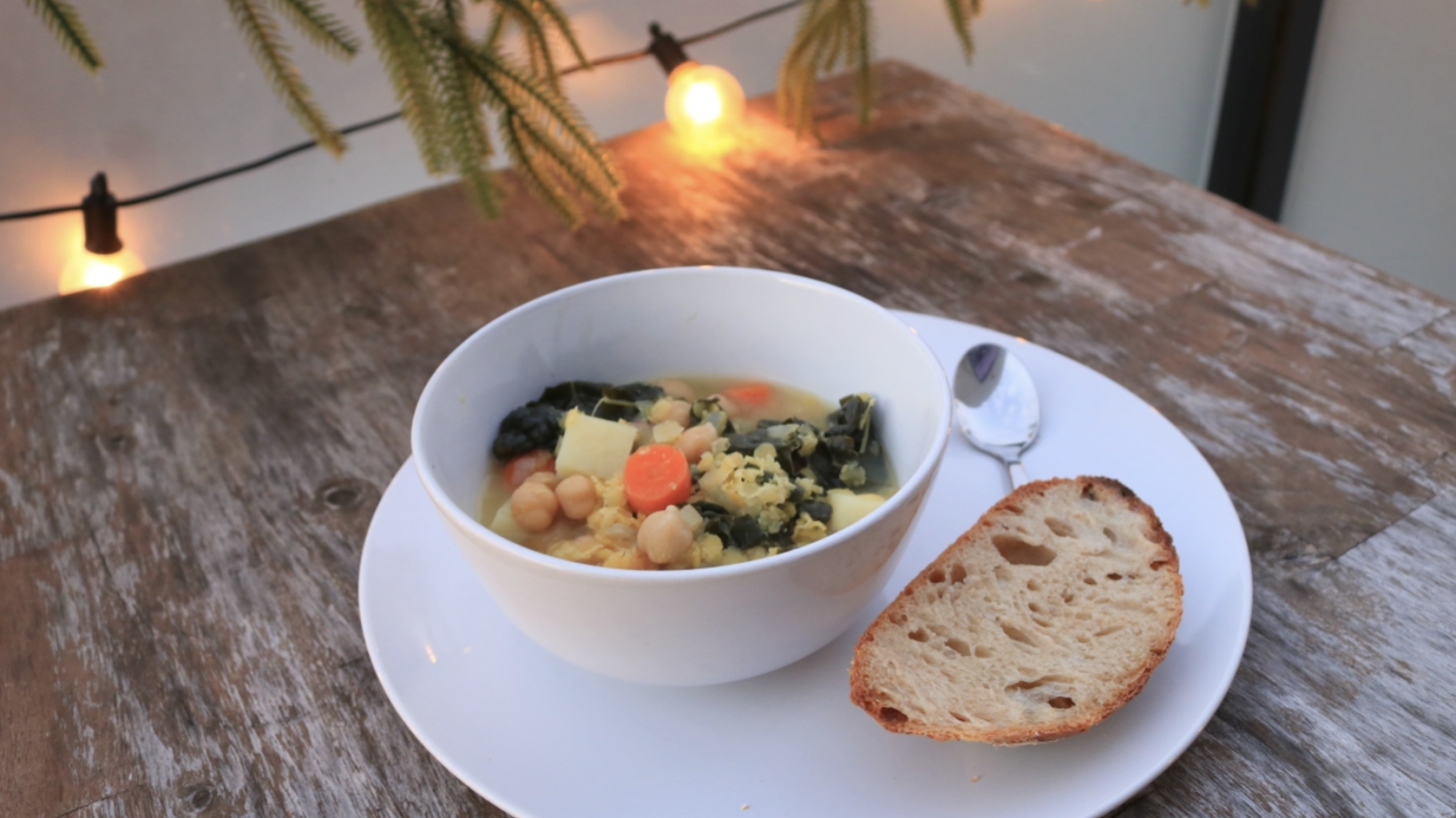 Un bol de soupe avec une tranche de pain copieux sur une vieille table en bois à l'extérieur.