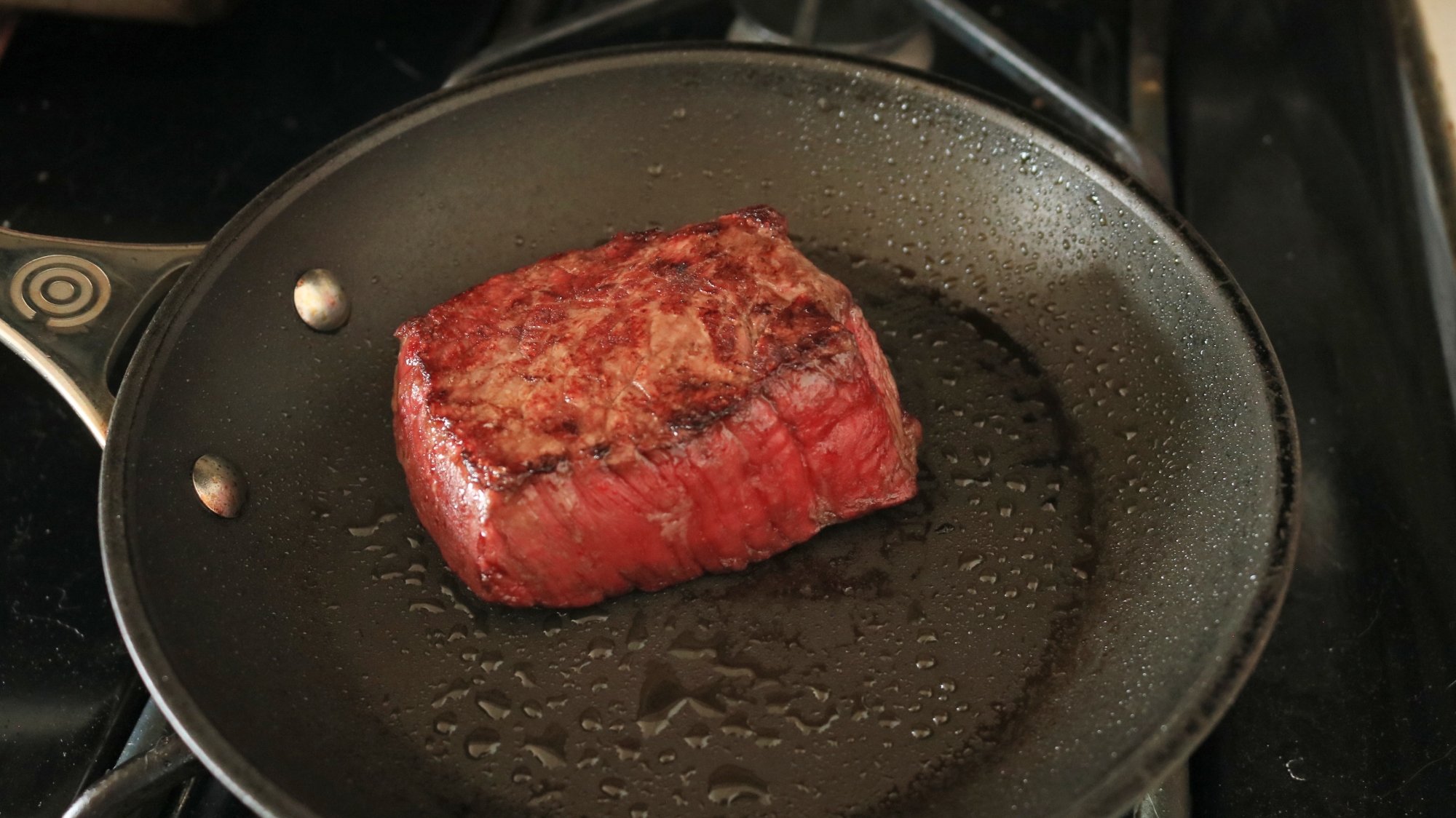 Un steak saisissant dans une poêle.
