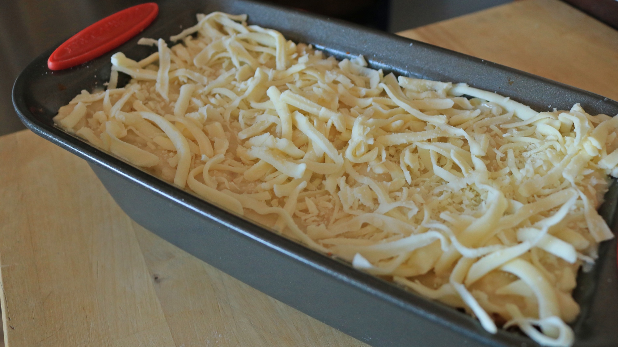 Lasagne dans une poêle à pain garni de fromage.