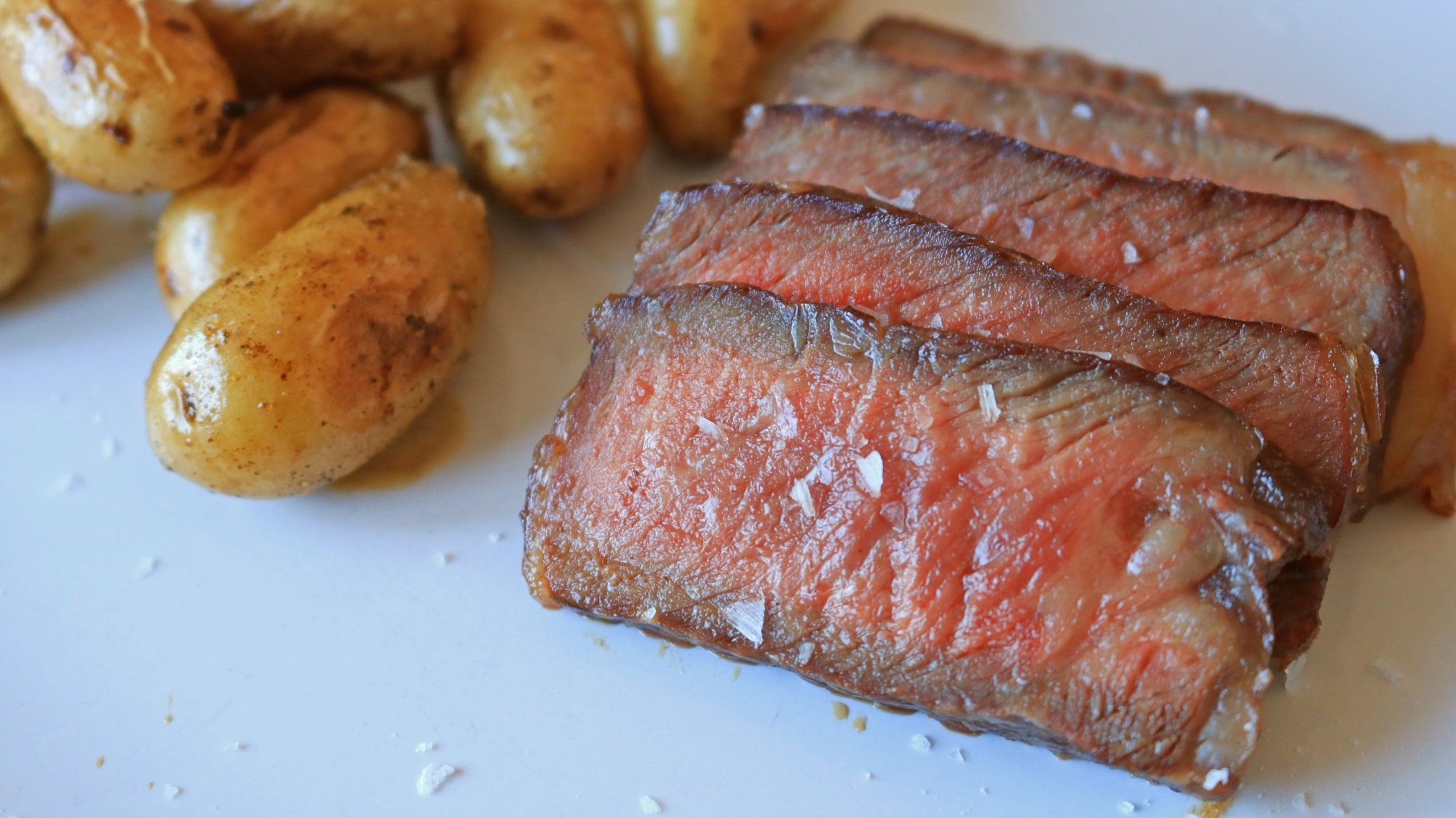 Steak tranché sur une assiette avec de petites pommes de terre dorées.