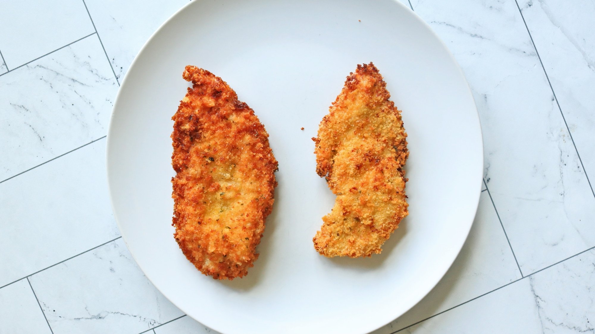 Deux escalopes de poulet sur une assiette blanche.